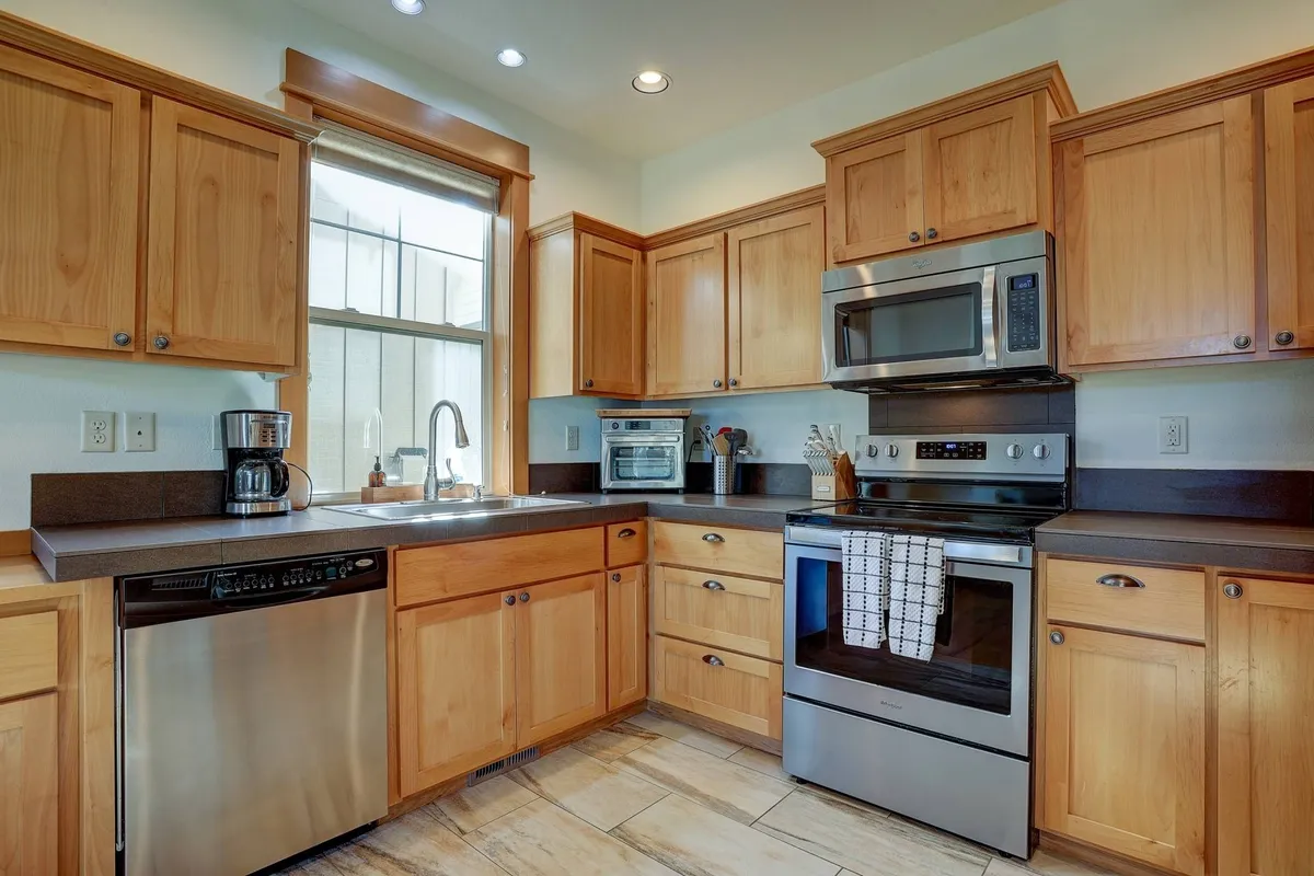 A warm, inviting kitchen with stainless steel appliances, wooden cabinetry, and a window over the sink. The ample countertop space and open layout make it ideal for family gatherings and entertaining guests.