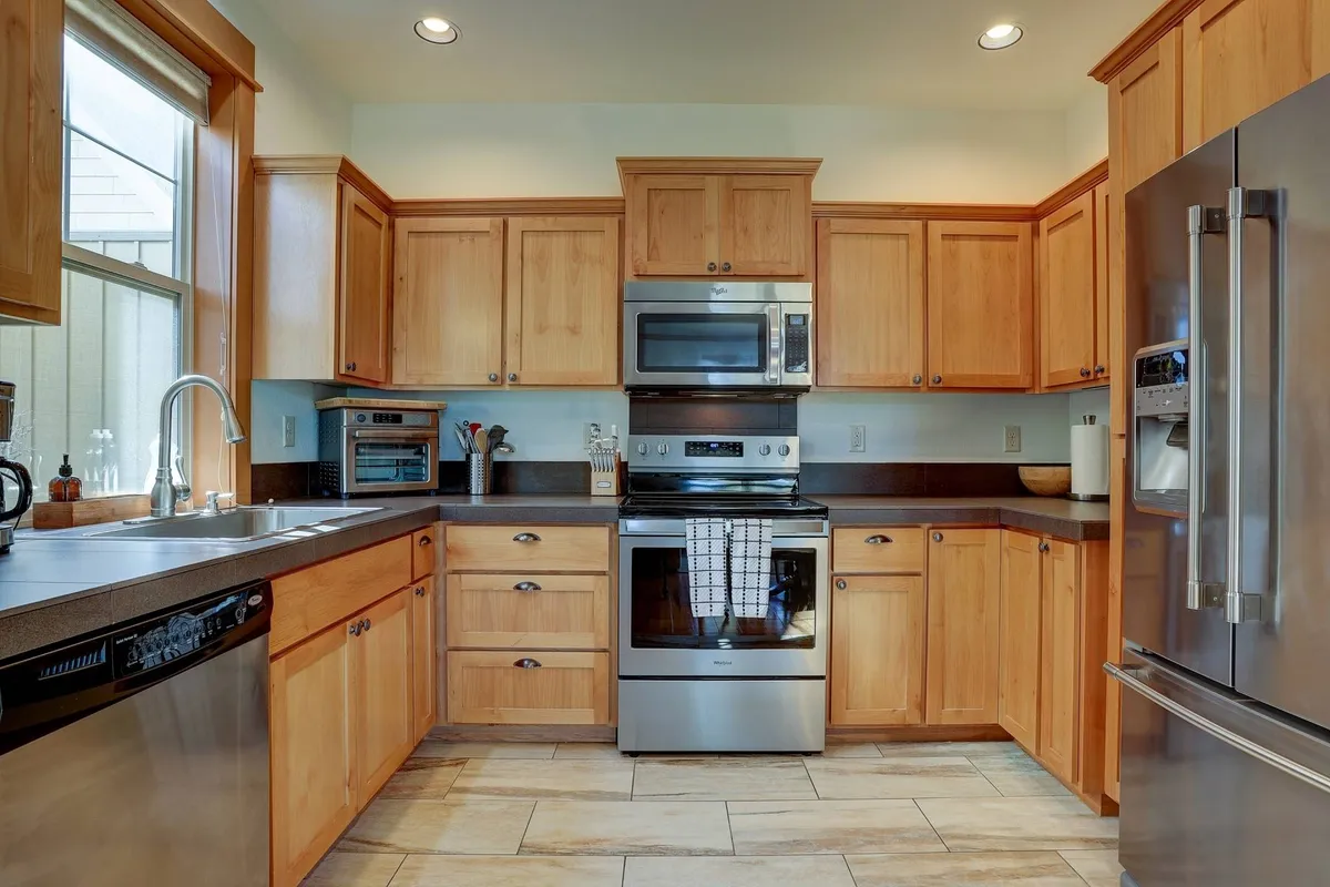 A functional and inviting kitchen with stainless steel appliances, wooden cabinets, and a central island. The setting is ready for meal preparation, family cooking sessions, and entertaining guests.