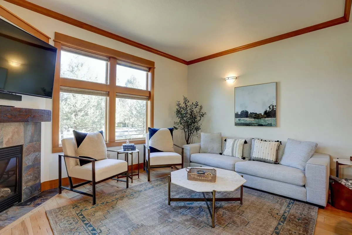 A bright, inviting living room featuring a comfortable sofa, large windows that let in ample sunlight, a stylish coffee table, and thoughtfully selected artwork. The overall atmosphere is cozy and relaxing, perfect for unwinding after a day out.