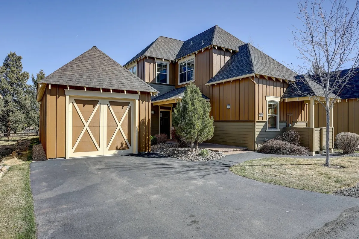 A welcoming exterior view of the Bunk House, capturing the main entrance, garage, landscaped yard, and roofline. The soft evening light gives the scene a warm and inviting feel, hinting at family gatherings and outdoor playtime in the spacious yard.