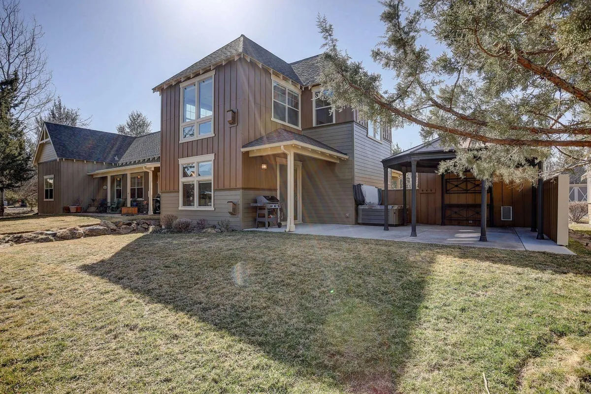 A welcoming exterior view of a two-story house, featuring a front porch, patio area, and neatly landscaped yard. The scene is set during golden hour, emphasizing the inviting and peaceful atmosphere with sunset views visible from the porch. The space hints at outdoor relaxation and privacy.